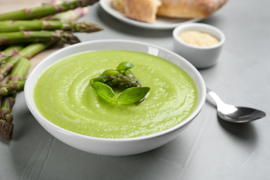 Photo of Delicious asparagus soup served on grey table, closeup