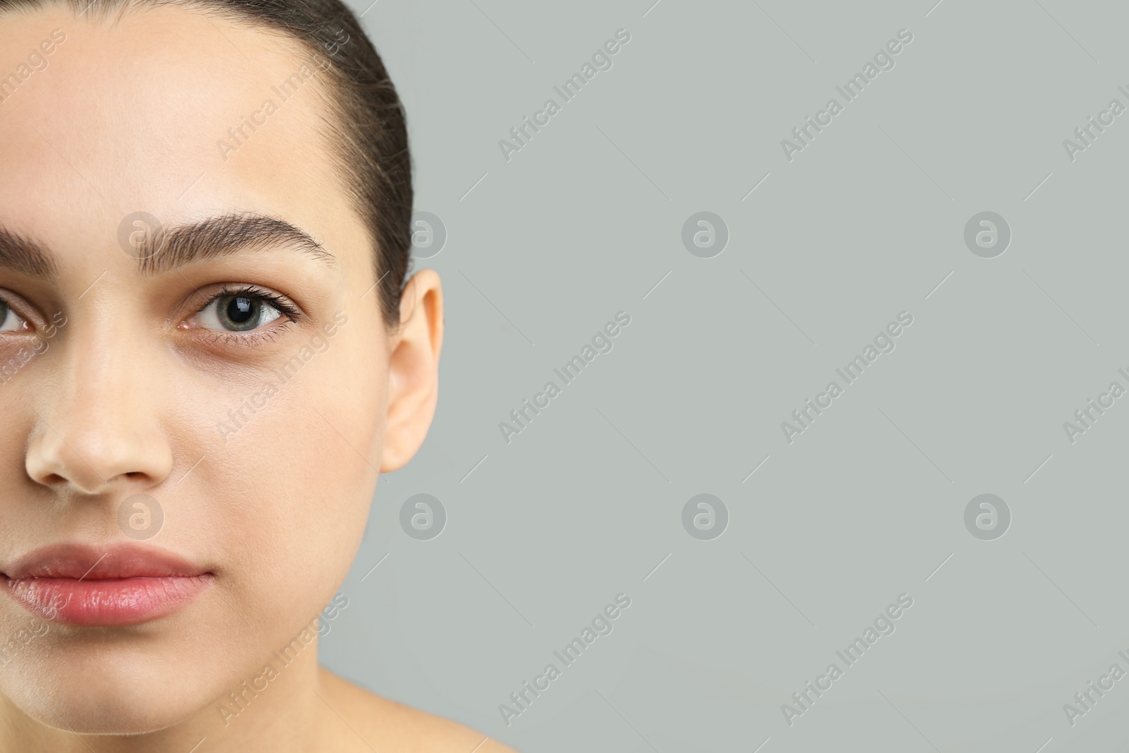 Photo of Young woman with perfect eyebrows on grey background, closeup. Space for text