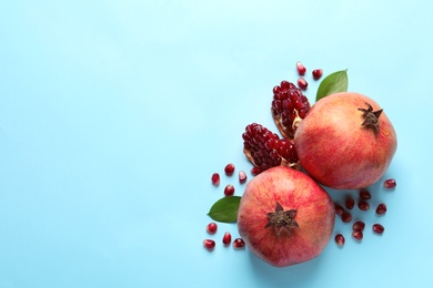 Ripe pomegranates and leaves on color background, top view with space for text