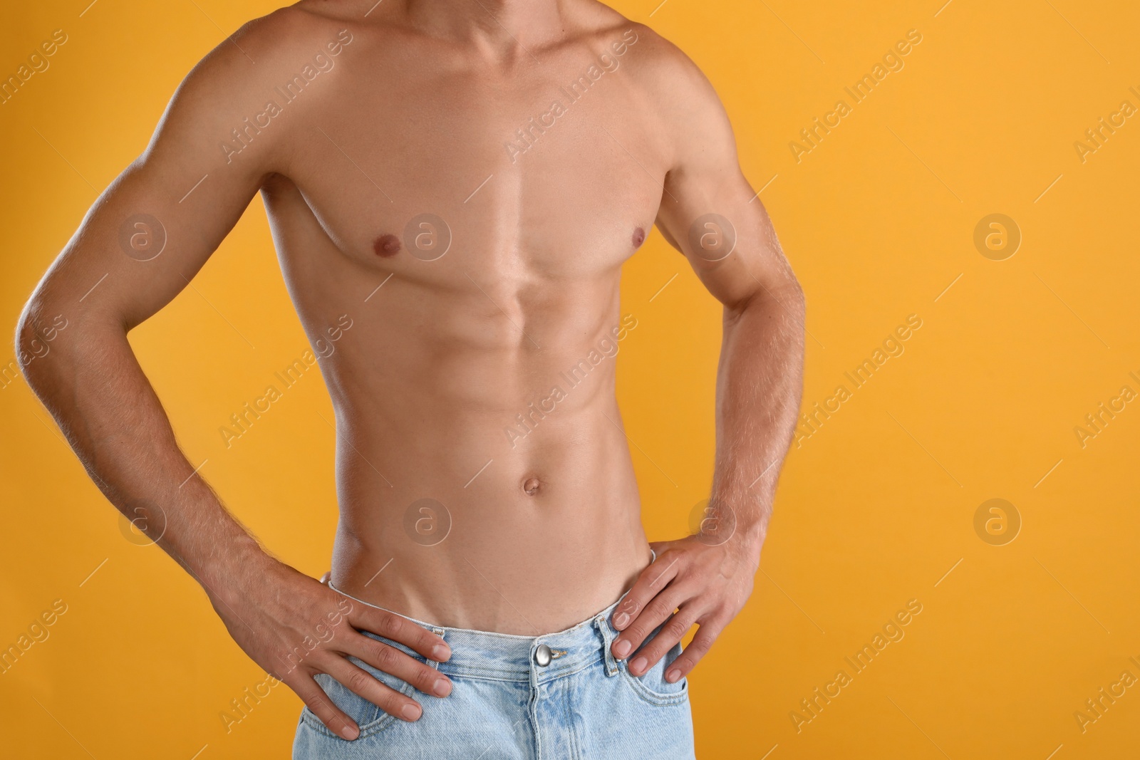 Photo of Shirtless man with slim body on yellow background, closeup