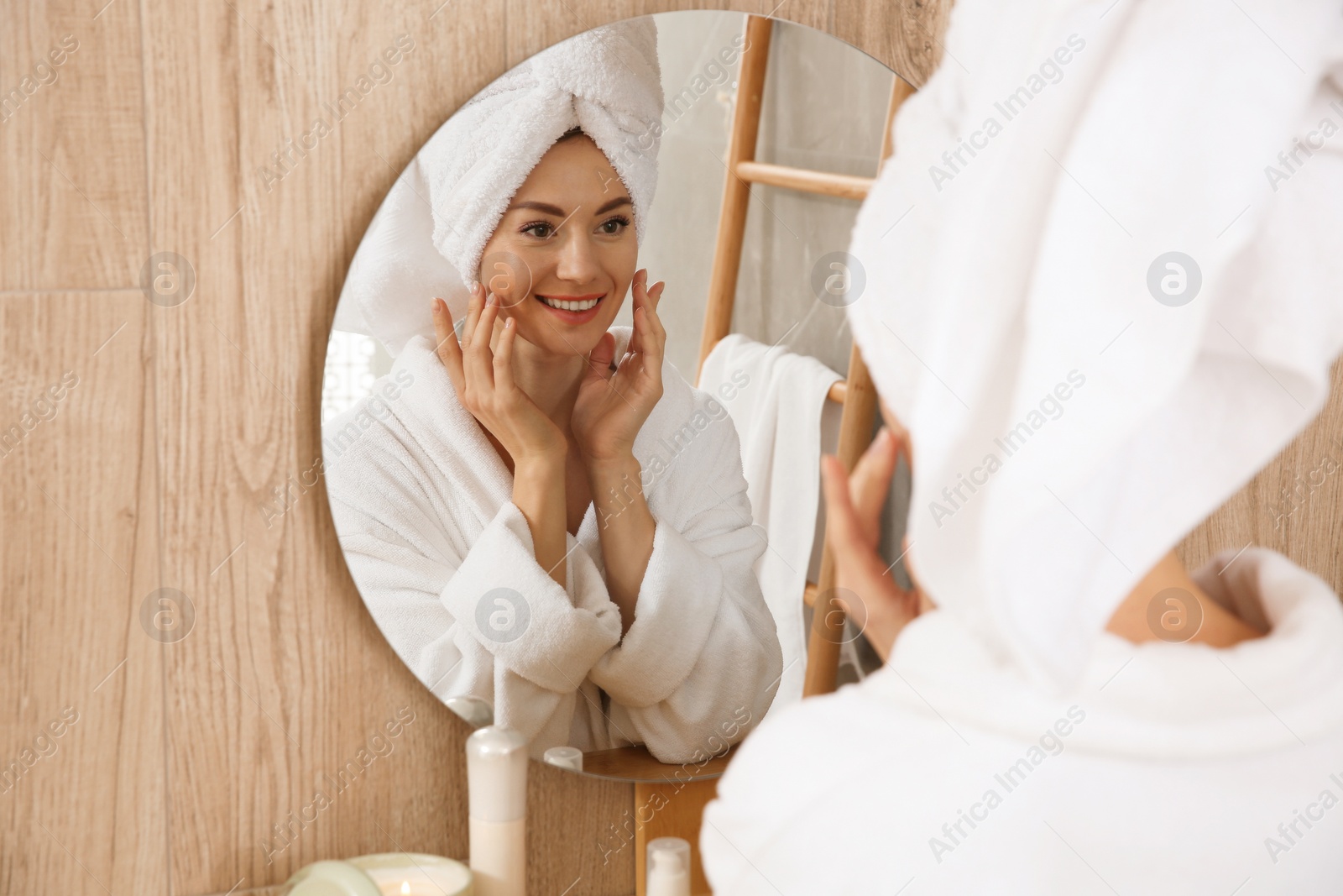 Photo of Beautiful woman wearing white bathrobe in front of mirror at home