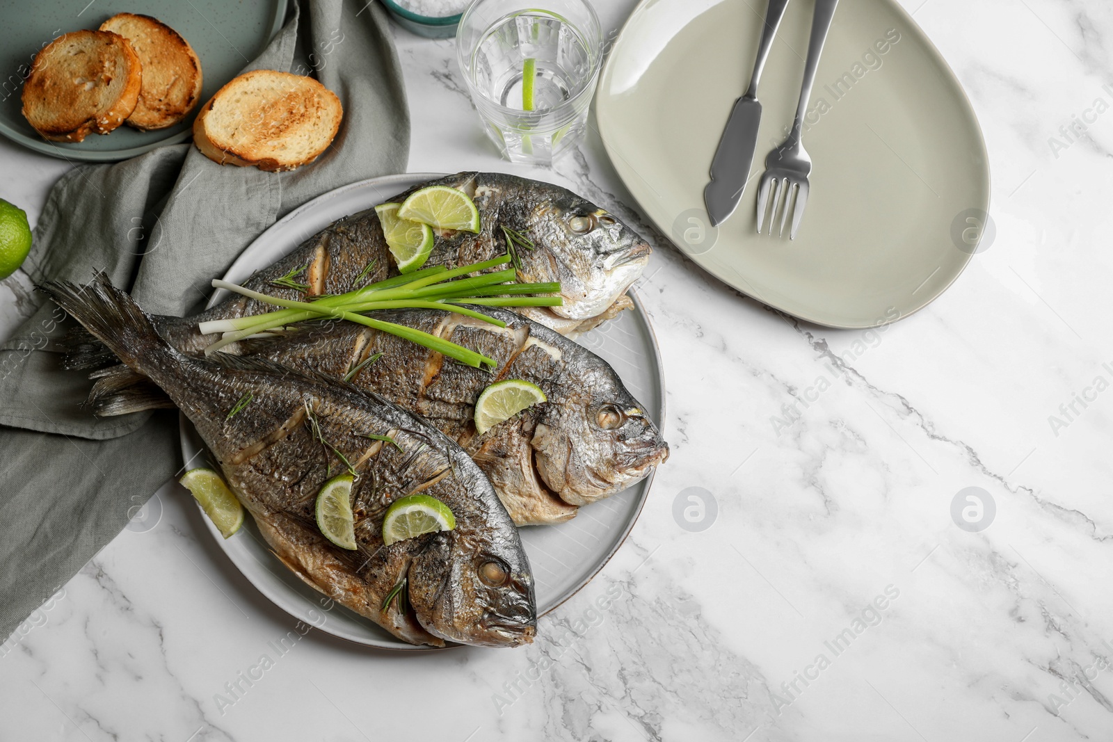 Photo of Seafood. Delicious baked fish served on white marble table, flat lay. Space for text