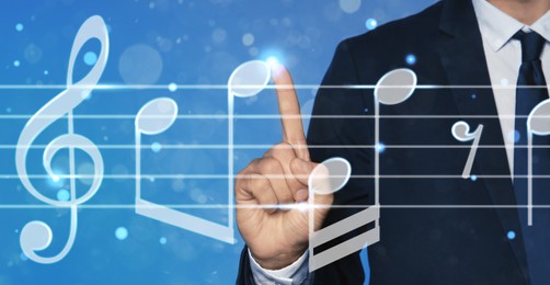 Musician pointing at staff with music notes and symbols on color background, closeup. Banner design