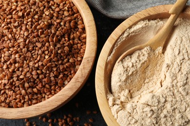 Photo of Buckwheat flour and grains in bowls on black table, top view