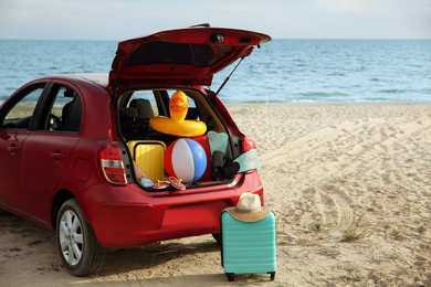 Red car luggage on beach, space for text. Summer vacation trip