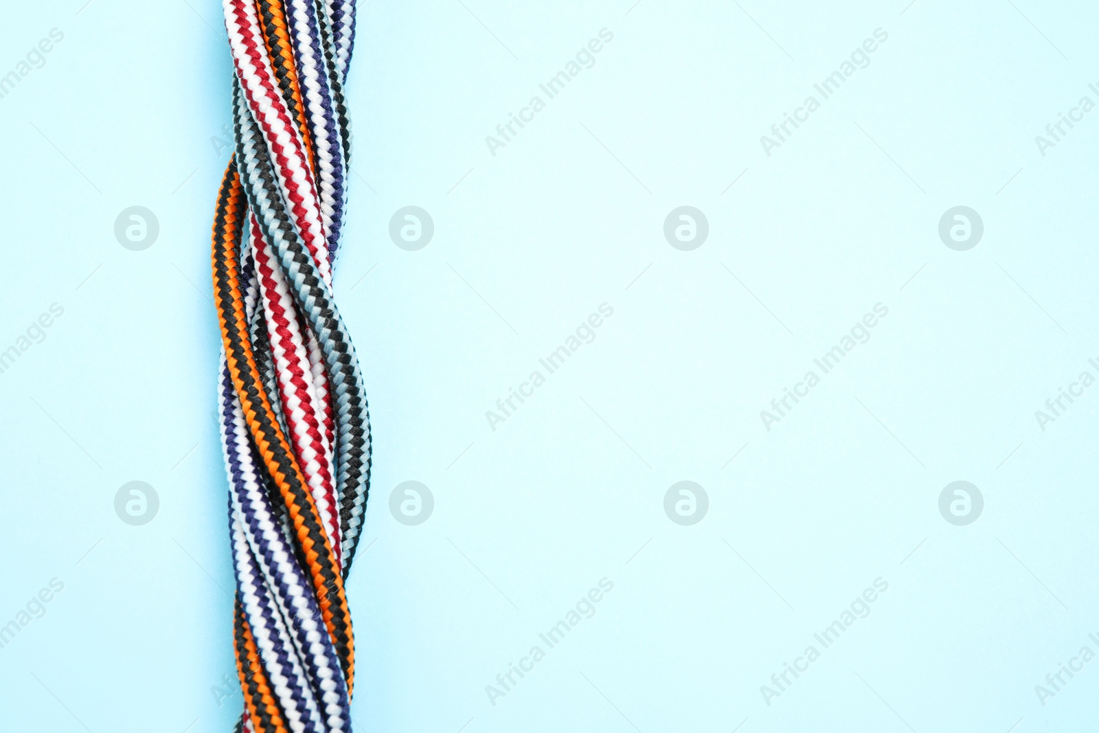 Photo of Top view of twisted colorful ropes on light blue background, space for text. Unity concept