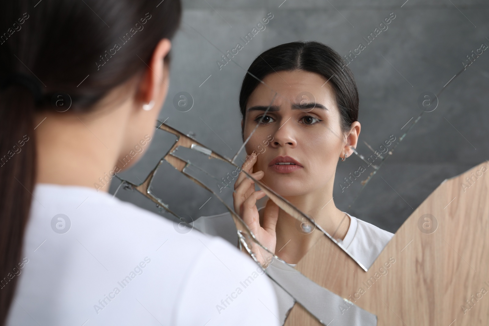 Photo of Young woman suffering from mental problems near broken mirror indoors