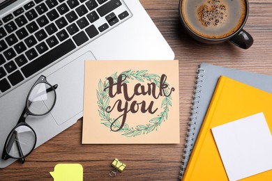 Photo of Card with phrase Thank You, laptop, glasses and notebooks on wooden table, flat lay