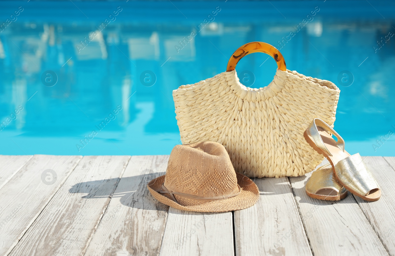 Photo of Beach accessories on wooden deck near outdoor swimming pool, space for text