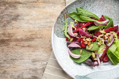 Photo of Plate with delicious beet salad on wooden background, top view