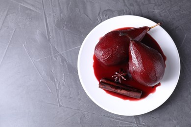 Tasty red wine poached pears and spices on grey table, top view. Space for text