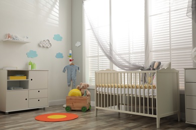 Stylish baby room interior with crib and toys