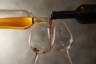 Pouring different wines from bottles into glasses on dark background