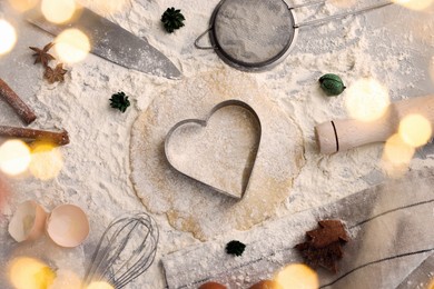 Flat lay composition with heart shaped cookie cutter, dough and ingredients on table