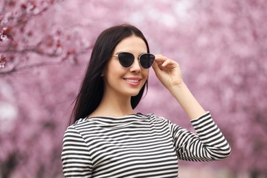 Photo of Pretty young woman in park with blooming trees. Spring look