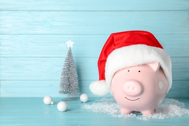 Photo of Composition with piggy bank and Christmas decor on table. Space for text