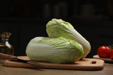 Fresh Chinese cabbages, knife, tomatoes and oil on wooden table