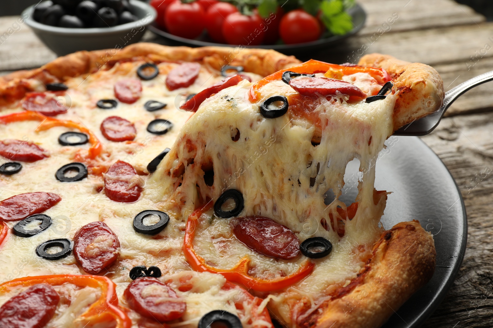 Photo of Taking piece of tasty pizza at table, closeup