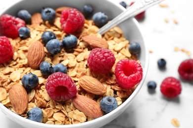 Photo of Tasty homemade granola with berries on white marble table, closeup. Healthy breakfast