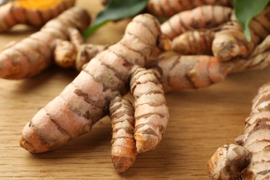 Photo of Many raw turmeric roots on wooden table, closeup