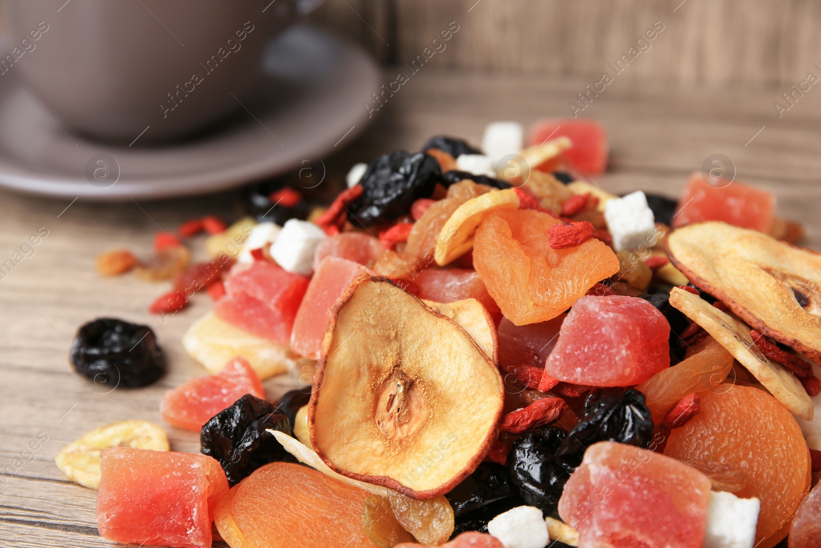 Photo of Pile of different tasty dried fruits on wooden table, closeup