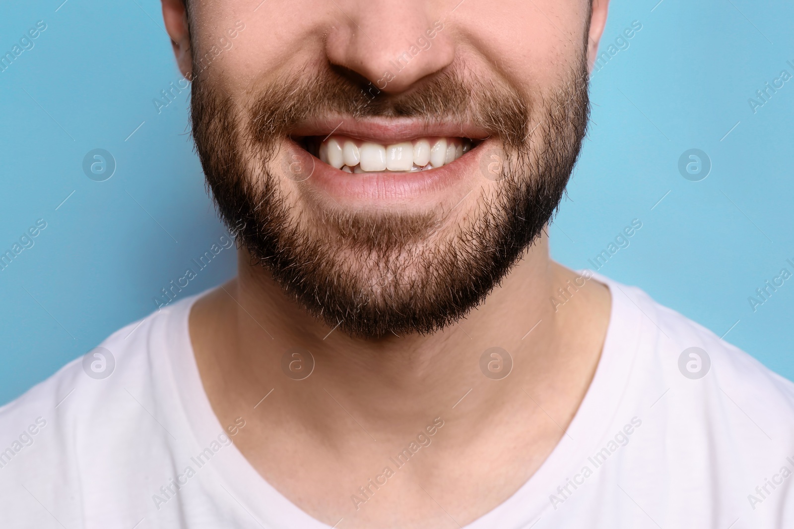 Photo of Young man with beautiful smile on grey background. Teeth whitening