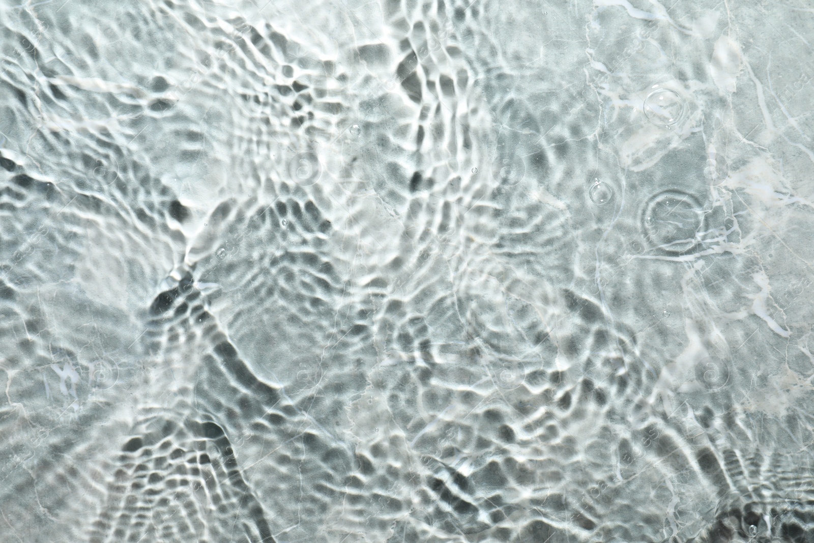 Photo of Rippled surface of clear water on light grey textured background, top view