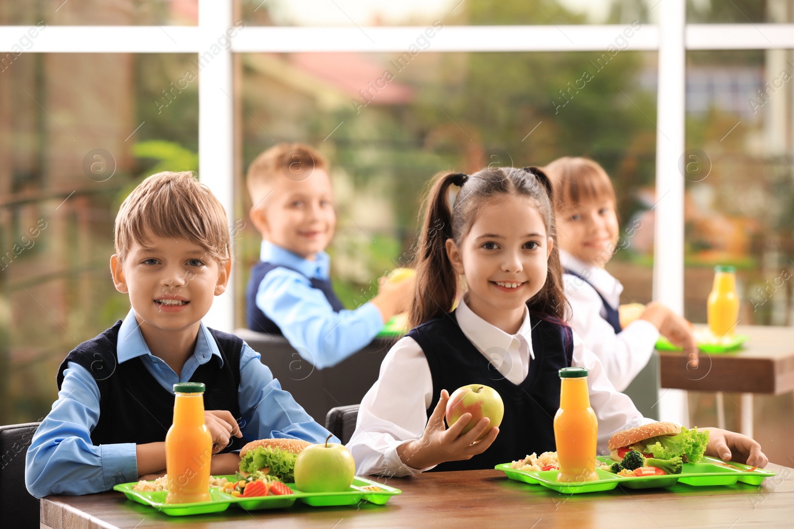 Photo of Happy children at table with healthy food in school canteen