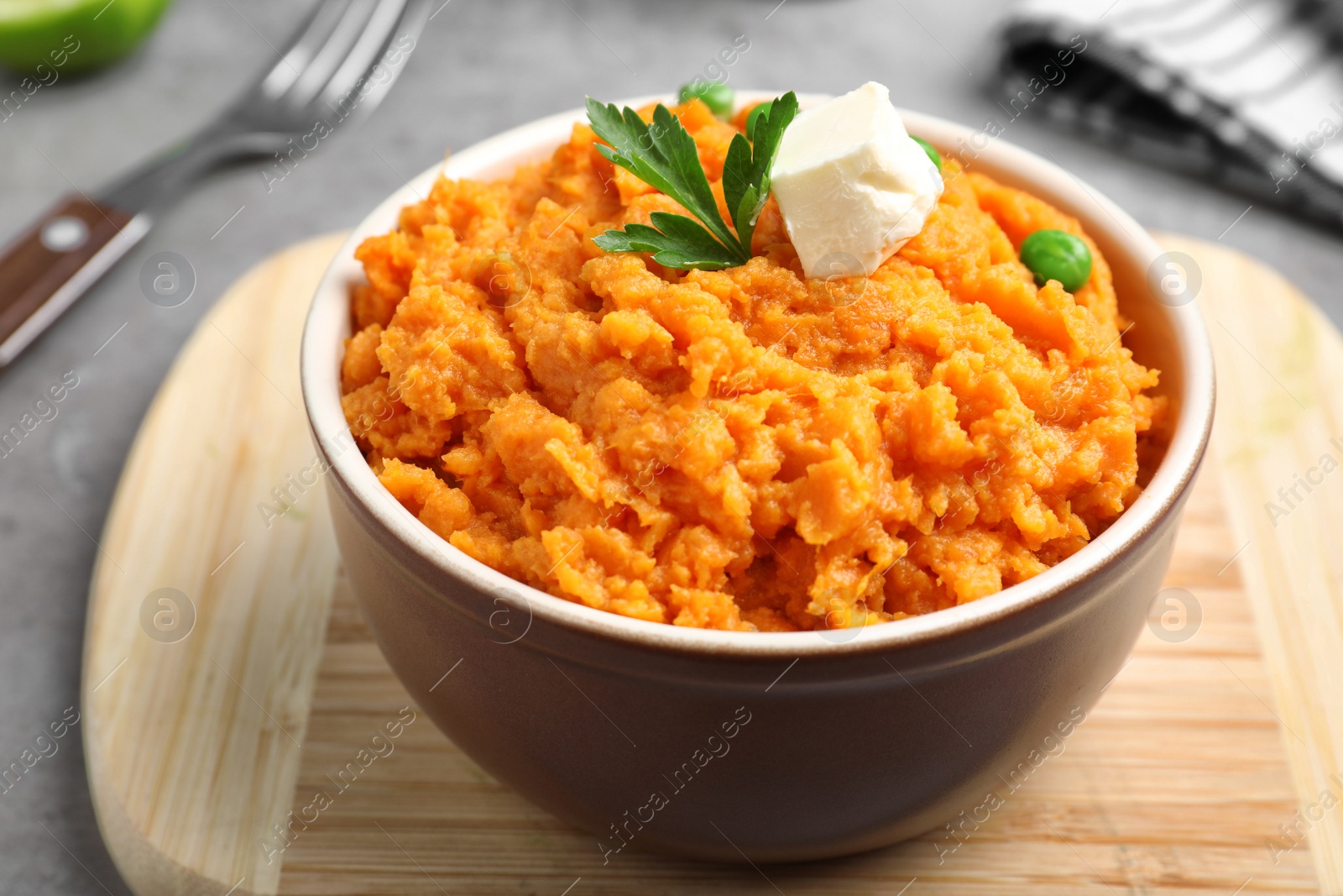 Photo of Board with bowl of tasty sweet potato puree on grey table