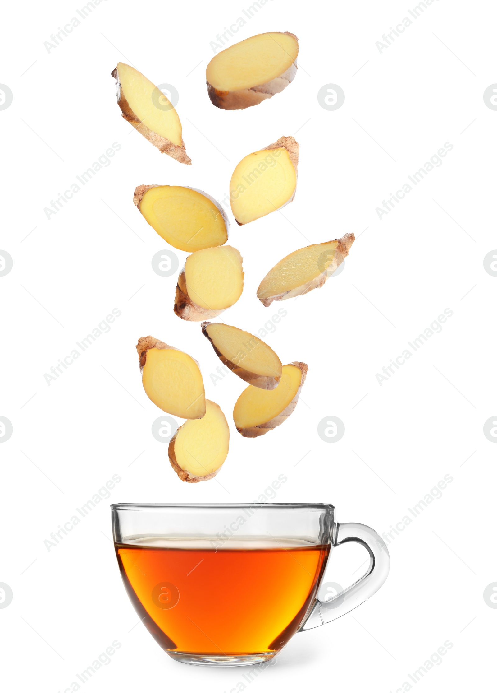 Image of Fresh sliced ginger falling into glass cup of tea on white background