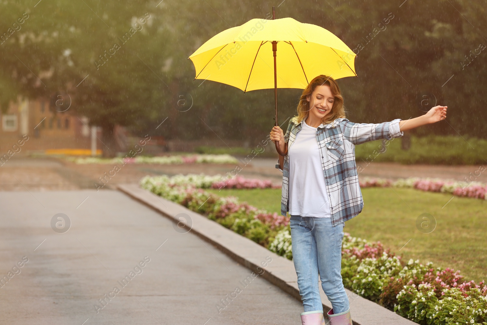 Photo of Happy young woman with umbrella under rain in park