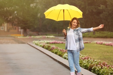 Happy young woman with umbrella under rain in park