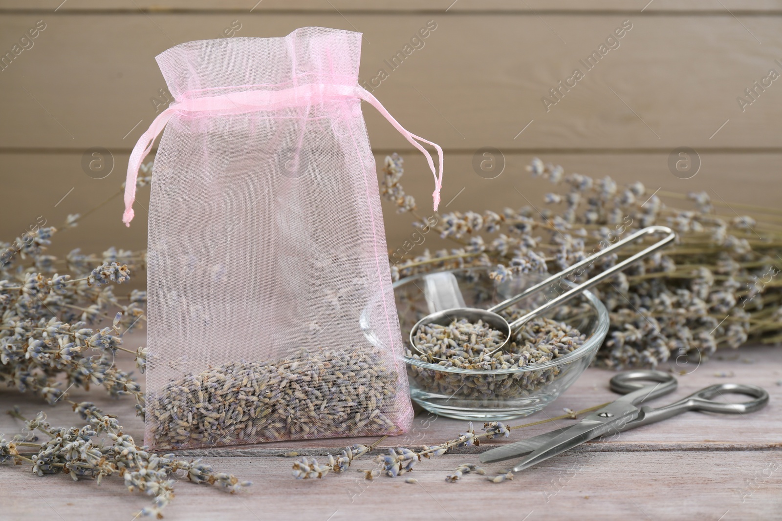 Photo of Scented sachet with dried lavender flowers and scissors on wooden table