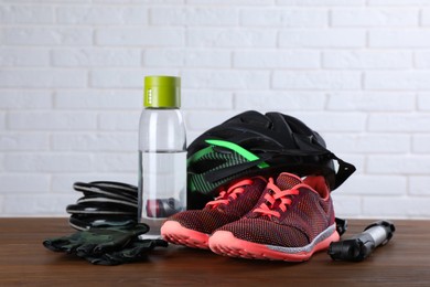 Different cycling accessories on wooden table against white brick wall