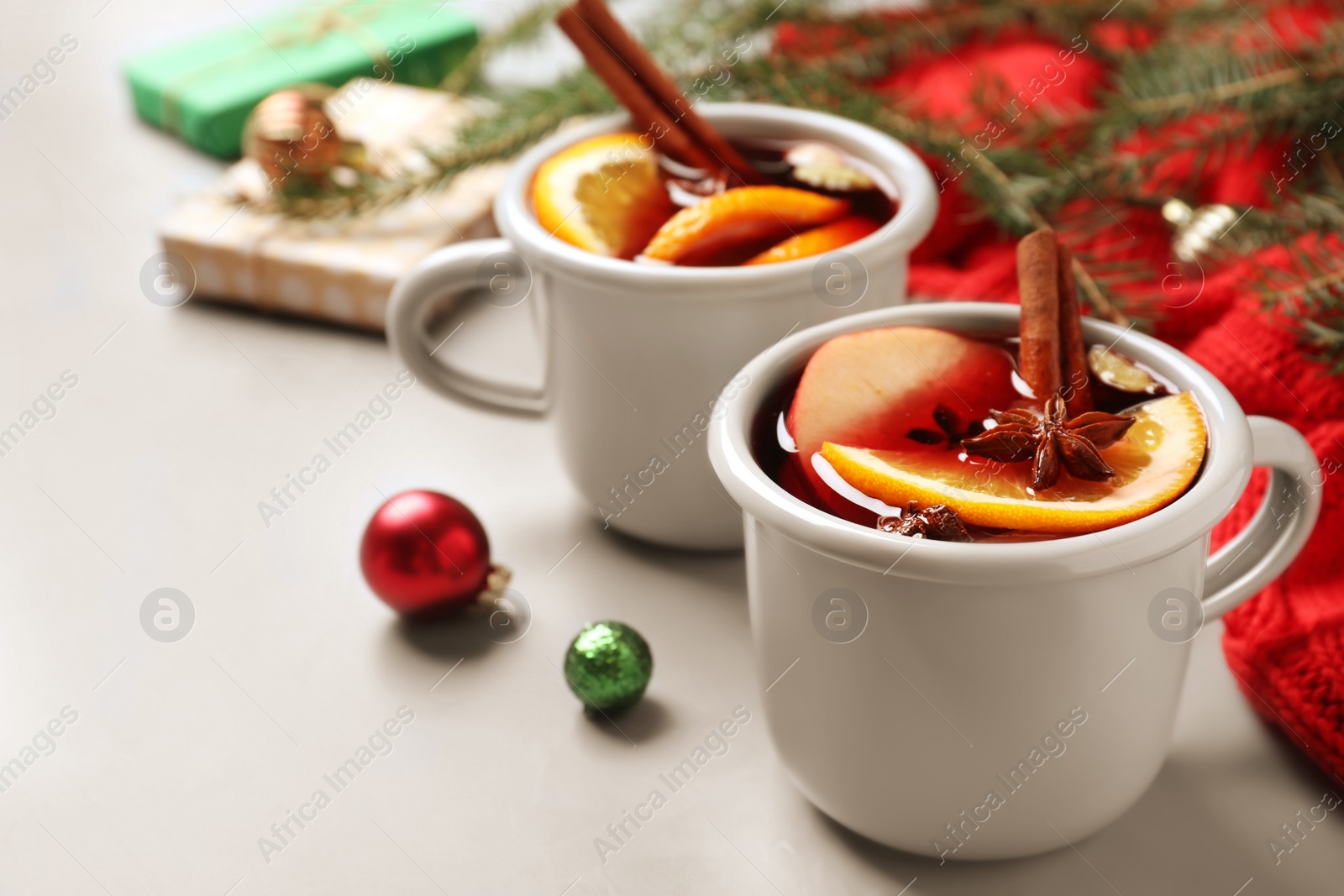 Photo of Cups of tasty mulled wine on grey table. Space for text