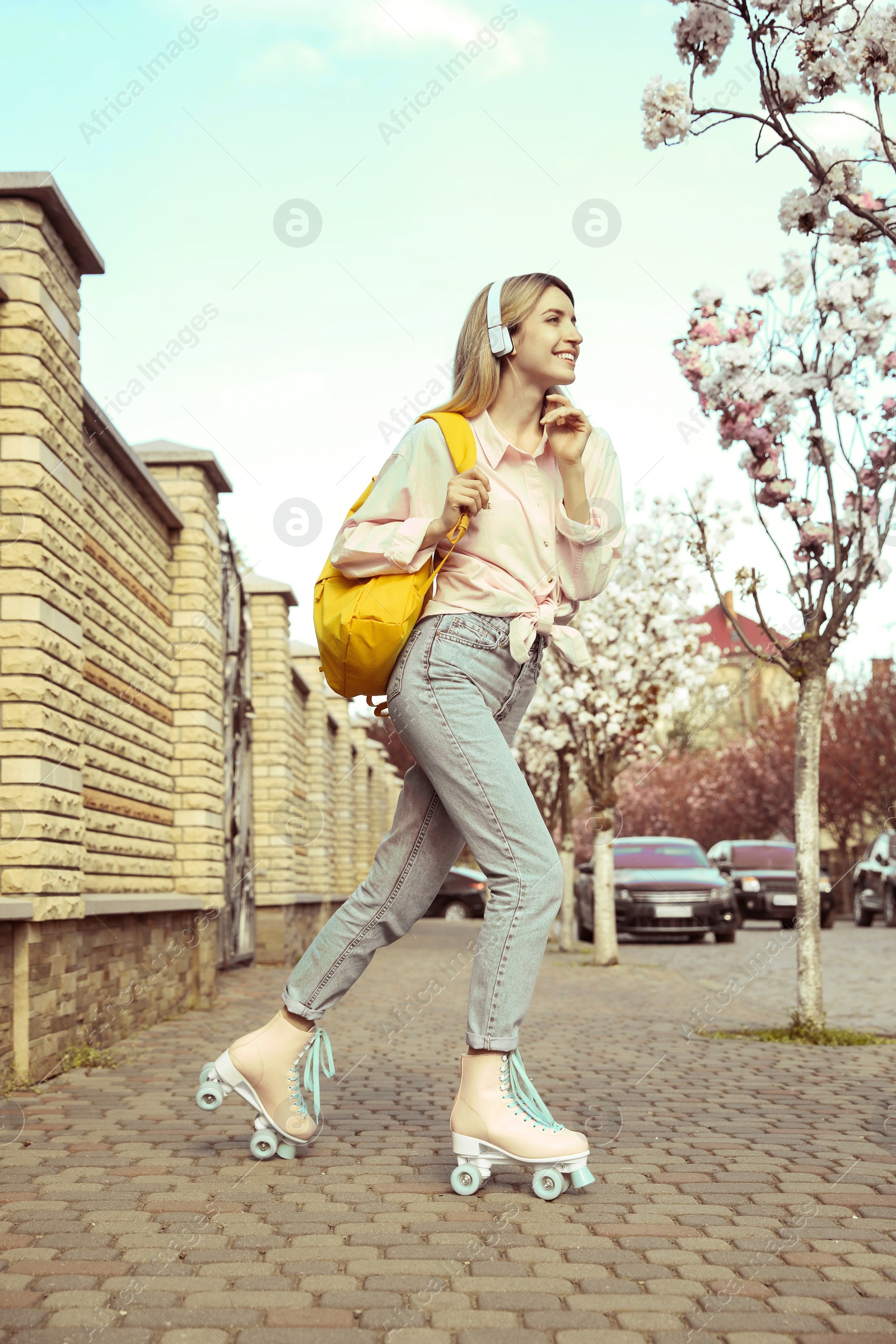 Image of Young woman roller skating on city street