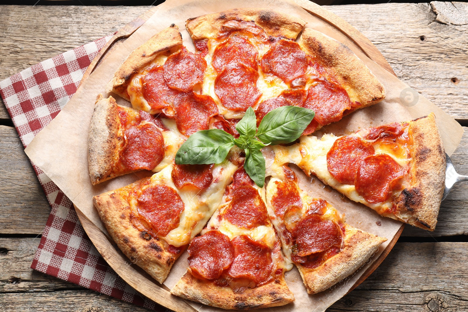 Photo of Tasty pepperoni pizza with basil on wooden table, top view