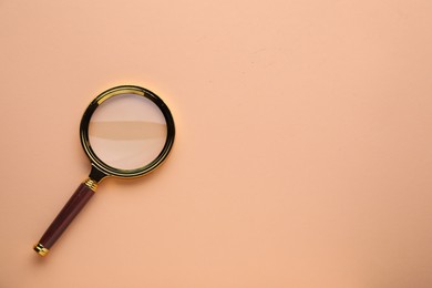 Magnifying glass on beige background, top view. Space for text