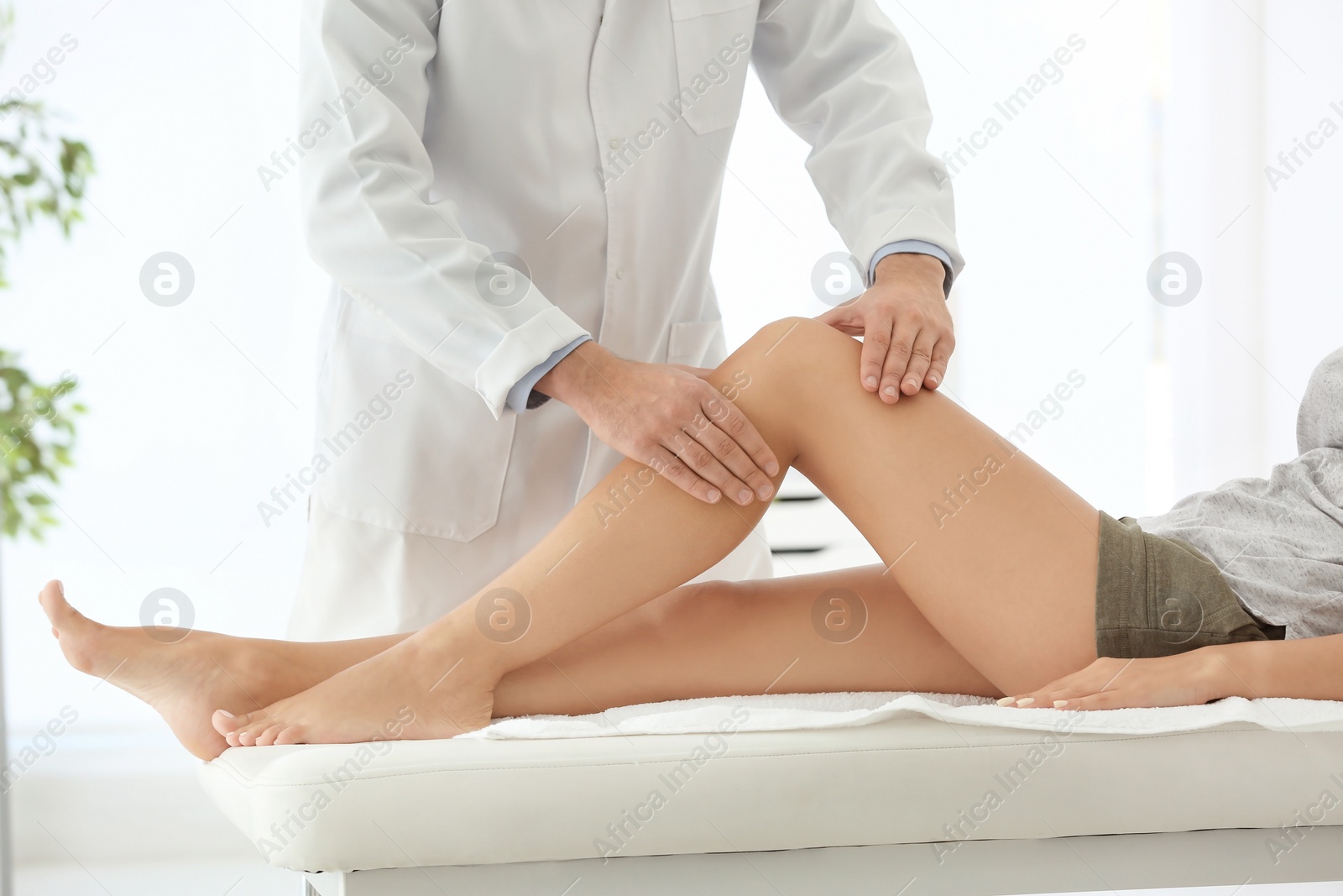 Photo of Doctor examining female patient with injured leg, closeup