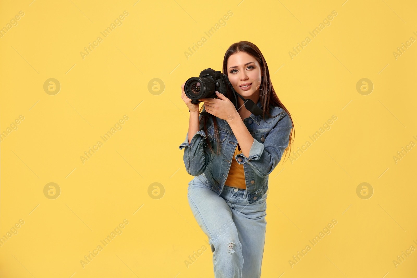 Photo of Professional photographer working on yellow background in studio