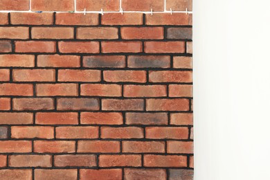 Photo of Decorative bricks with tile leveling system on white wall