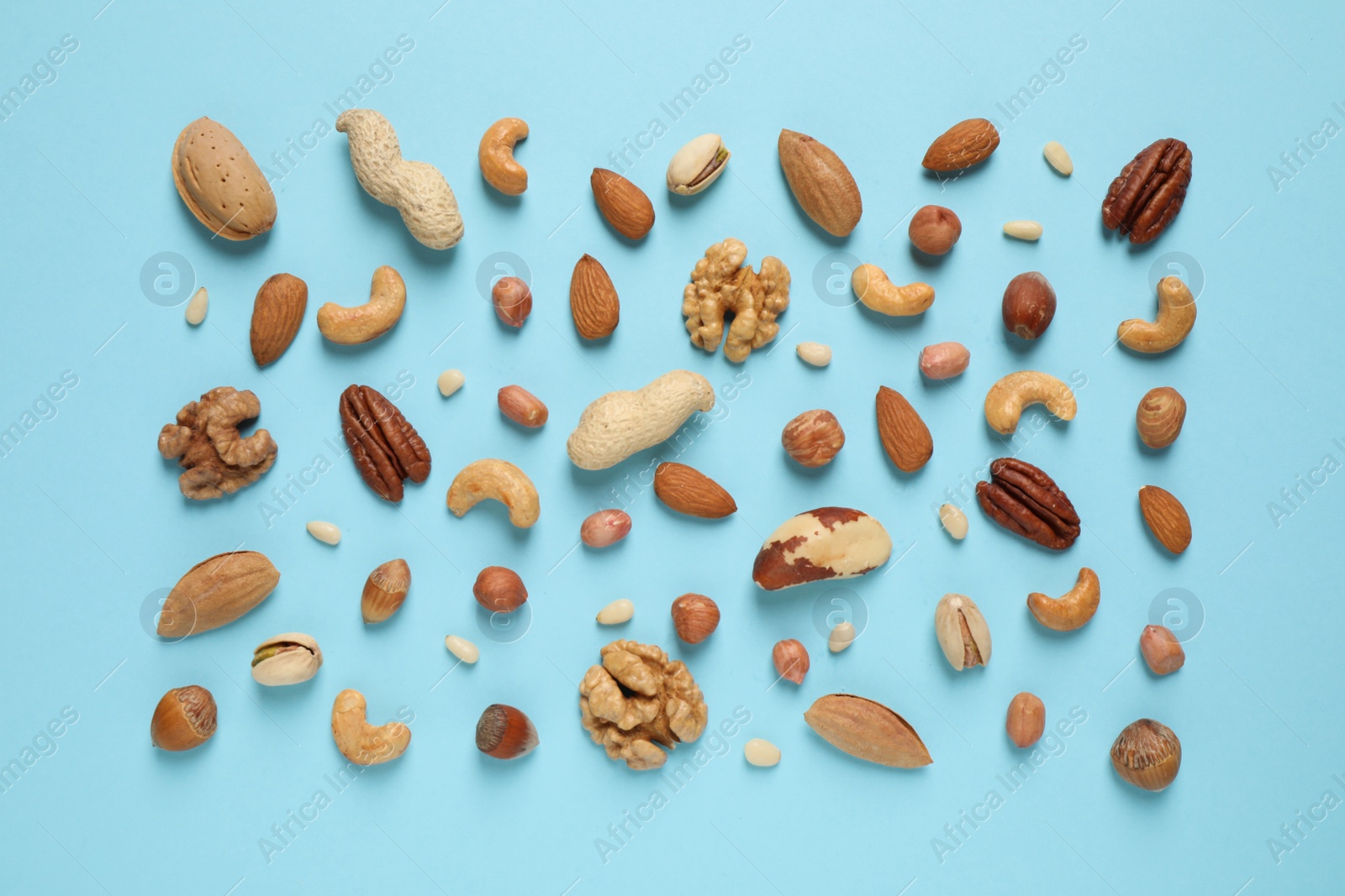 Photo of Different delicious nuts on light blue background, flat lay