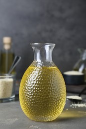 Fresh sesame oil in glass bottle on grey table