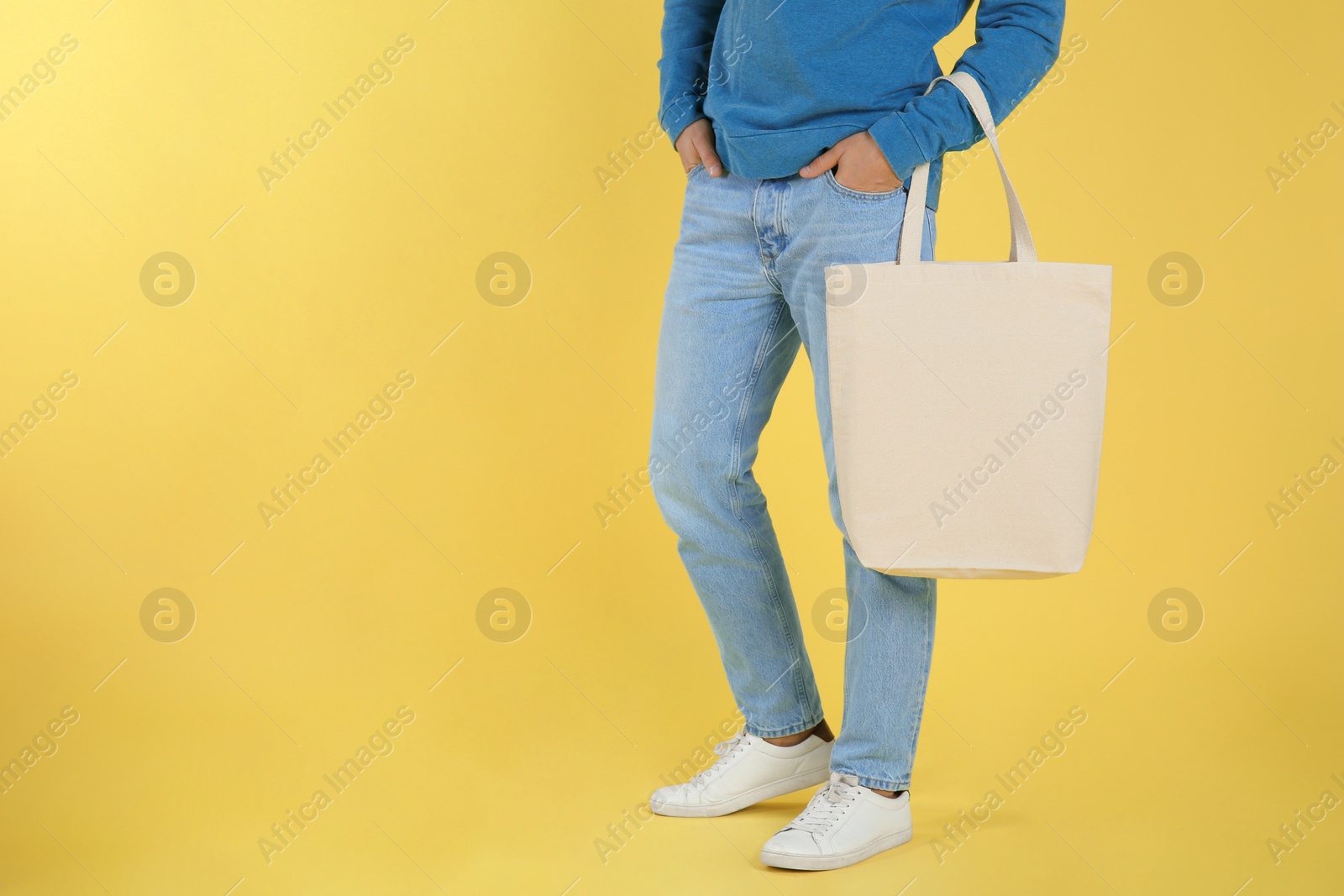 Photo of Young man holding textile bag on color background, closeup. Mockup for design