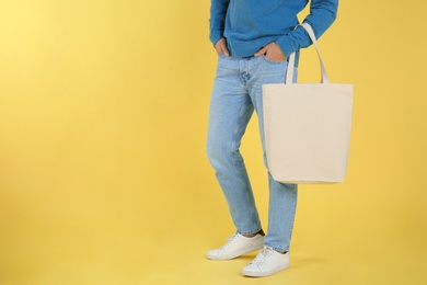 Photo of Young man holding textile bag on color background, closeup. Mockup for design