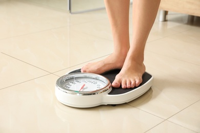 Photo of Woman standing on scales in bathroom. Overweight problem
