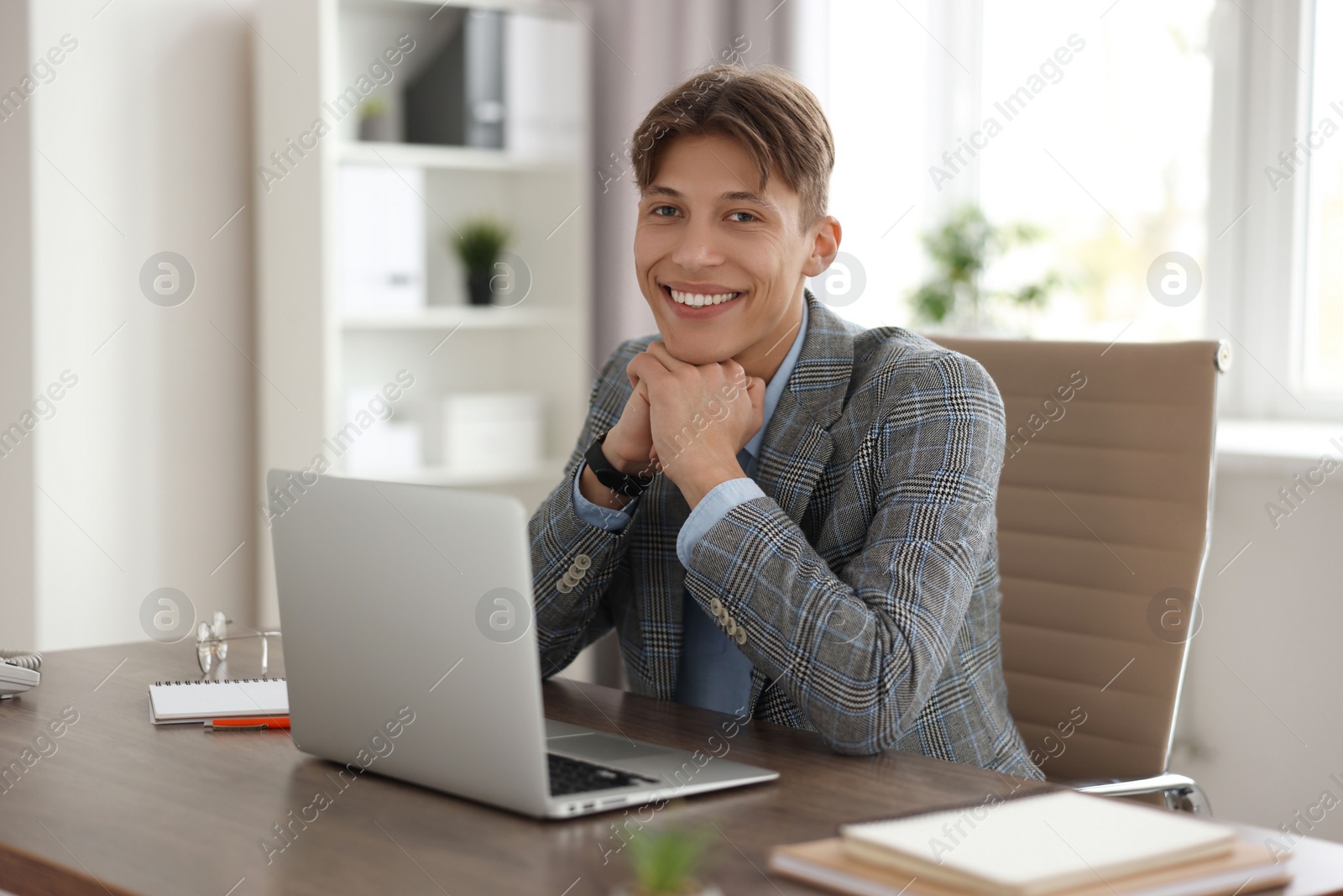 Photo of Man watching webinar at wooden table in office