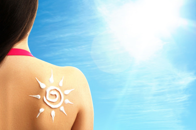 Young woman with sun protection cream on her back outdoors, closeup. Space for text