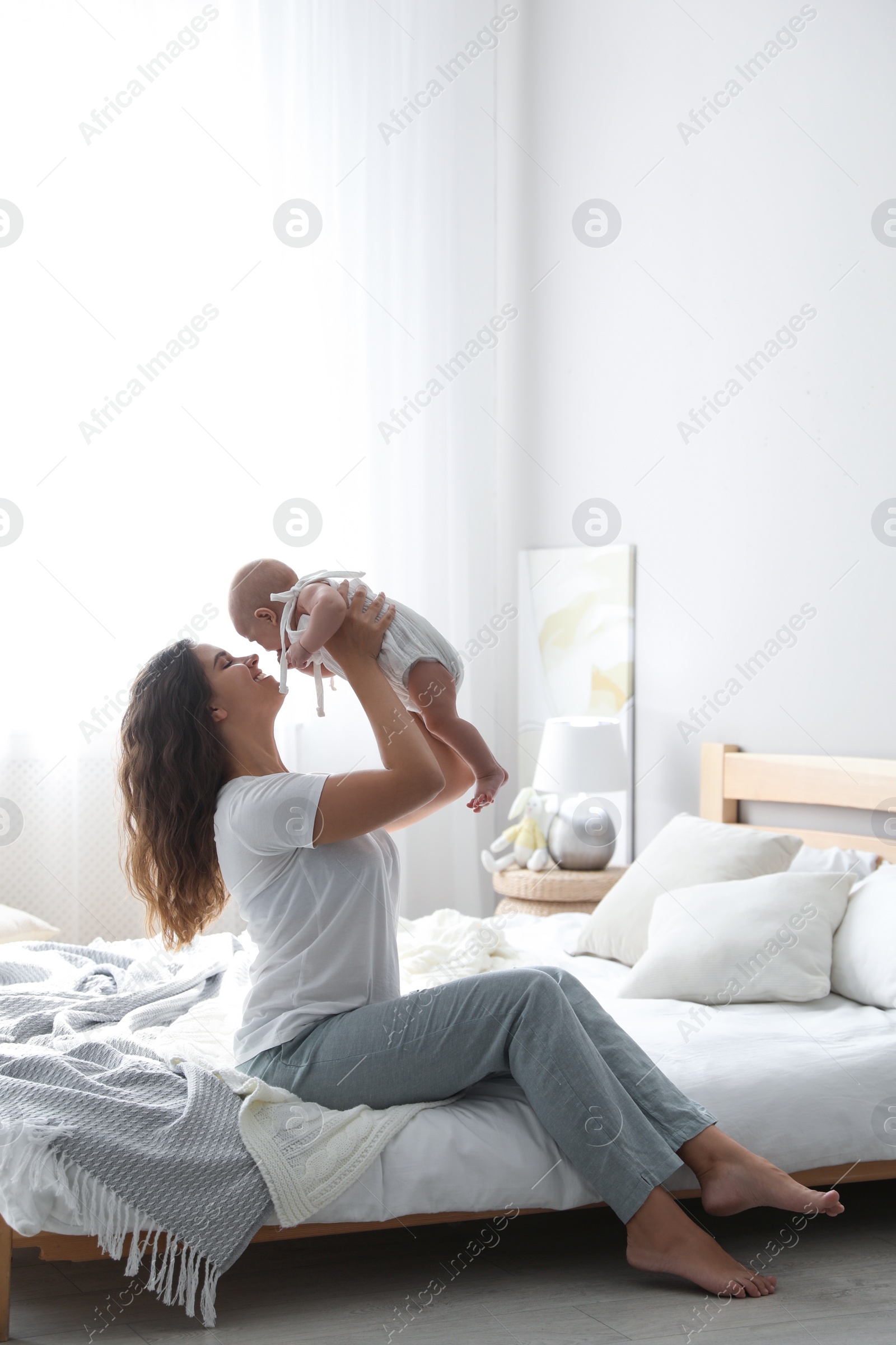 Photo of Happy young mother with her cute baby on bed at home