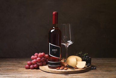 Bottle of red wine with glass and appetizers on wooden table